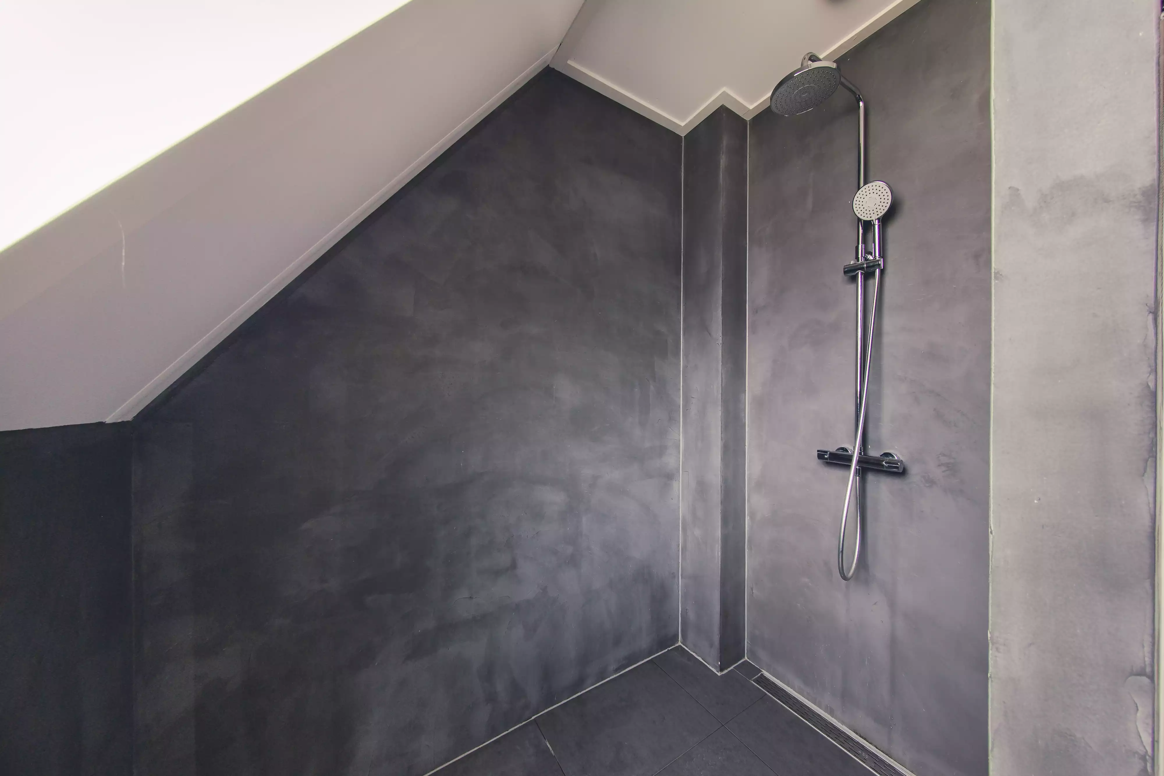 een badkamer met donkere beton cire door uwvloerafwerking.nl geplaatst